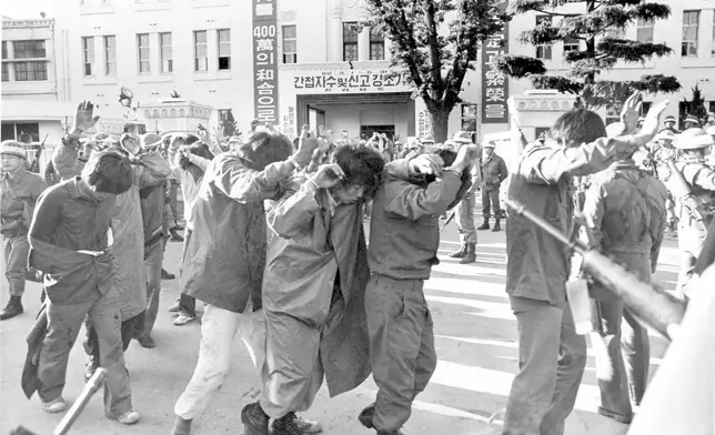 FILE- Scores of captured rebels with hands up are being led away Tuesday May 27, 1980, by armed soldiers from the provincial government HQ., in this city of Gwangju (Kwangju) which South Korean troops recaptured in a firefight earlier in the day. (AP Photo)