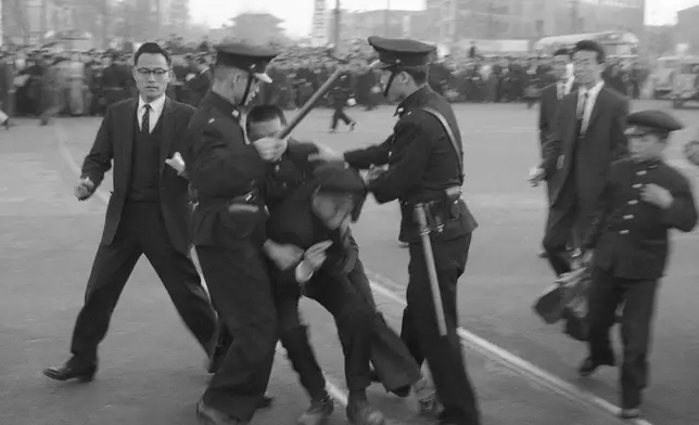 FILE- Two policemen flank demonstrators in Seoul, South Korea on April 18, 1960 using clubs to break up a riot protesting the March 15 presidential election. Demonstrations continued and on April 19 in the South Korean capital martial law was declared. (AP Photo, File)