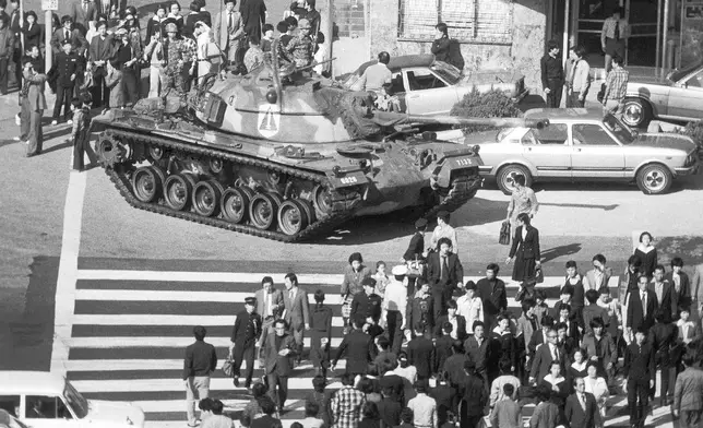 FILE- Seoul citizens walk beside an army tank on Saturday, Oct. 27, 1979, after martial law was declared following the death of President Park Chung-Hee. (AP Photo/Kim Chon-Kil, File)