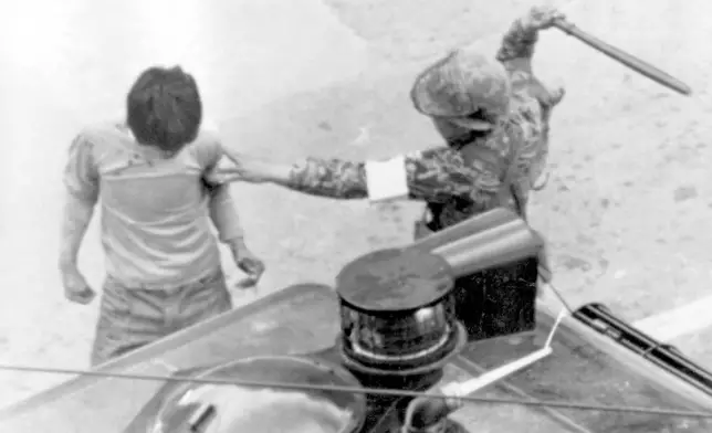 FILE- A helmeted army paratroops beats a man arrested during violent anti-government demonstrations in Gwangju (Kwangju), May 20, 1980. (AP Photo/File)