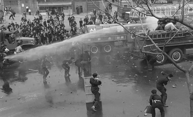 FILE- Students in South Korea capital of Seoul use shield to defy attempts to disperse them with fire hoses on April 19, 1960. Students were protesting manner in which recent election was managed. (AP Photo/Kim Chon Kil, File)
