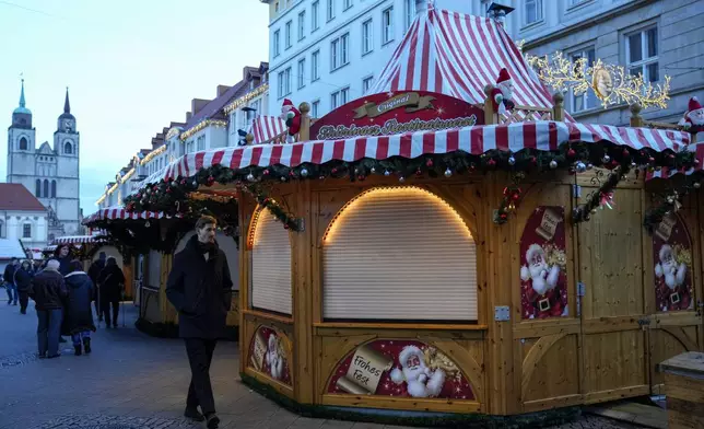 People walk at the Christmas Market, where a car drove into a crowd on Friday evening, in Magdeburg, Germany, Sunday, Dec. 22, 2024. (AP Photo/Ebrahim Noroozi)