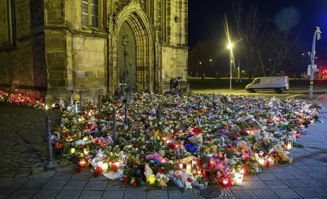 Flowers, candles, wreaths and stuffed animals lie in front of St. John's Church, Monday, Dec. 23, 2024, in Madgeburg, Germany, after a car drove into a Christmas market on Friday. (Klaus-Dietmar Gabbert/dpa via AP)