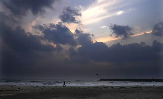 A man collects plastic bottles left on the beach in Nagapattinam, one of the severely damaged town during 2004 tsunami, India, Sunday, Dec. 15, 2024. (AP Photo/Mahesh Kumar A.)