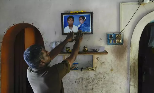 G. Ramesh prays to then photograph of his parents who died during 2004 Tsunami at his residence in Keechankuppam, Nagapattinam, India, Sunday, Dec. 15, 2024. (AP Photo/Mahesh Kumar A.)