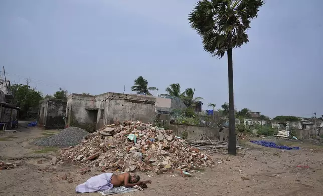 A man sleeps on a beach in Nagapattinam, one of the severely damaged town during 2004 tsunami, India, Monday, Dec.16, 2024. (AP Photo/Mahesh Kumar A.)