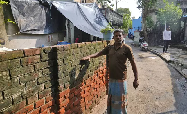 G. Ramesh shows the height of the water, while recalling his memories of 2004 Tsunami outside his home in Nagapattinam, India, Sunday, Dec. 15, 2024. (AP Photo/Mahesh Kumar A.)