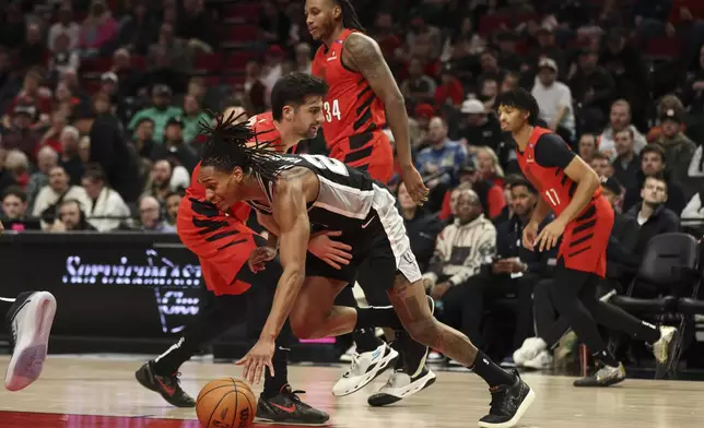 San Antonio Spurs guard Devin Vassell (24) dribbles up the court as Portland Trail Blazers forward Deni Avdija (8) grabs for the ball during the first half of an NBA basketball game Friday, Dec. 13, 2024, in Portland, Ore. (AP Photo/Amanda Loman)