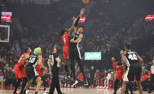 Portland Trail Blazers forward Jerami Grant (9) and San Antonio Spurs center Victor Wembanyama (1) jump up for the tipoff during the first half of an NBA basketball game Friday, Dec. 13, 2024, in Portland, Ore. (AP Photo/Amanda Loman)