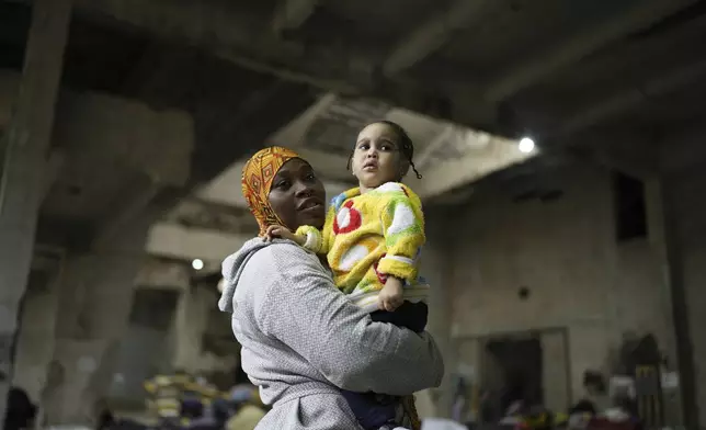 Sierra Leonean migrant worker Isatta Bah, 24, smiles as she holds her daughter, Blessing, one year old, during an interview with The Associated Press while waiting to be repatriated back home, as they are sheltered at a former car dealership in Hazmieh, east of Beirut, Lebanon, Wednesday, Dec. 4, 2024. (AP Photo/Hassan Ammar)