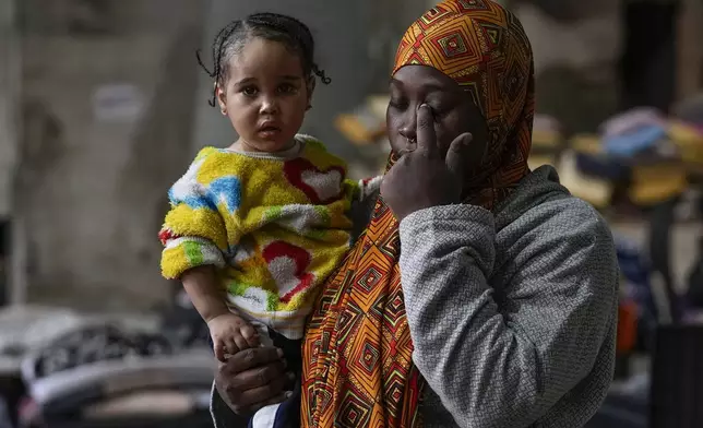 Sierra Leonean migrant worker Isatta Bah, 24, reacts as she holds her daughter, Blessing, one year old, during an interview with The Associated Press while waiting to be repatriated back home, as they are sheltered at a former car dealership that was turned into a shelter in Hazmieh, east of Beirut, Lebanon, Wednesday, Dec. 4, 2024. (AP Photo/Hassan Ammar)