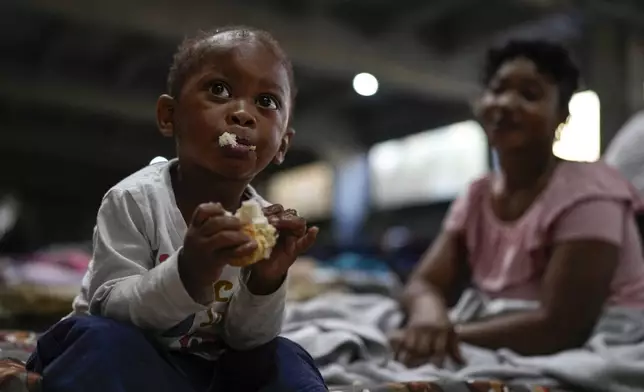 Mohammad, 3, son of a Sierra Leonean migrant worker stranded in Lebanon, eats bread as he waits to be repatriated back home with his mother, as they are sheltered at a former car dealership in Hazmieh, east of Beirut, Lebanon, Friday, Nov. 15, 2024. (AP Photo/Hassan Ammar)