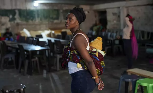 A Sierra Leonean migrant worker stranded in Lebanon with her baby, waits to be repatriated back home, as they are sheltered at a former car dealership that was turned into a shelter in Hazmieh, east of Beirut, Lebanon, Friday, Nov. 15, 2024. (AP Photo/Hassan Ammar)