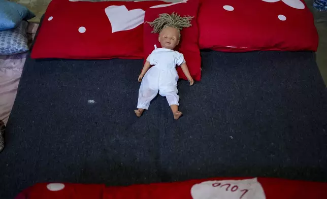 A baby doll is seen lying on a mattress belonging to a female Sierra Leonean migrant worker stranded in Lebanon, as she waits to be repatriated back home, while sheltered at a former car dealership in Hazmieh, east of Beirut, Lebanon, Friday, Nov. 15, 2024. (AP Photo/Hassan Ammar)