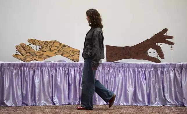 FILE - A woman walks past an artwork by Jasleen Kaur during the Turner Prize 2024 press preview at Tate Britain in London, Sept. 24, 2024. (AP Photo/Thomas Krych)