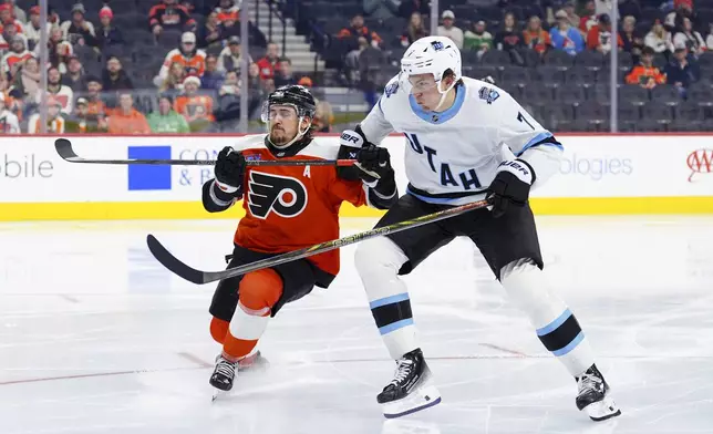 Philadelphia Flyers' Travis Konecny, left, and Utah Hockey Club's Michael Kesselring, right, race for the puck during the second period of an NHL hockey game, Sunday, Dec. 8, 2024, in Philadelphia. (AP Photo/Derik Hamilton)