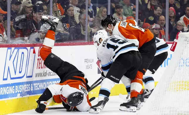 Philadelphia Flyers' Cam York, left, is upended as Flyers' Travis Sanheim (6) and Utah Hockey Club's Alexander Kerfoot (15) battle for the puck during the first period of an NHL hockey game, Sunday, Dec. 8, 2024, in Philadelphia. (AP Photo/Derik Hamilton)