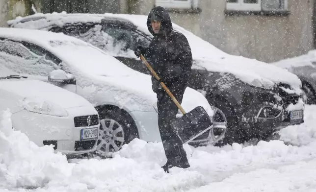 A man shovels snow from the street during heavy snowfall in Bihac, Bosnia, Monday, Dec. 23, 2024. (AP Photo/Edvin Zulic)