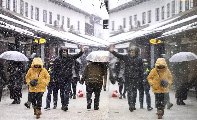 People walk in the street during heavy snowfall in downtown Sarajevo, Bosnia, Monday, Dec. 23, 2024. (AP Photo/Armin Durgut)