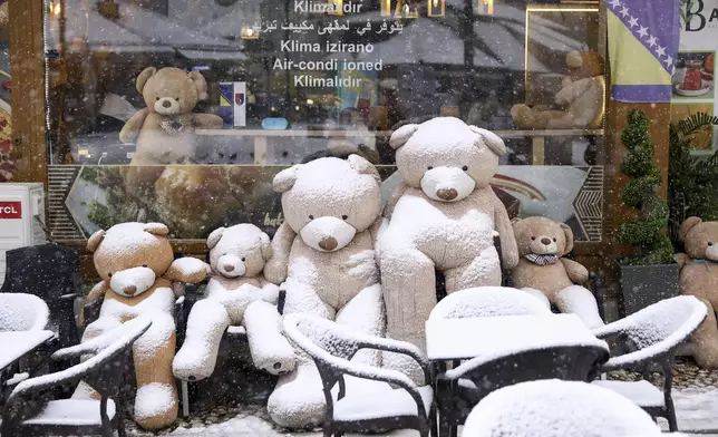 Teddy bears are seen covered with snow outside a cafe in downtown Sarajevo, Bosnia, Monday, Dec. 23, 2024. (AP Photo/Armin Durgut)