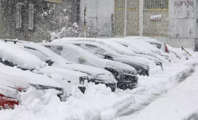 Cars are seen covered with snow during heavy snowfall in Bihac, Bosnia, Monday, Dec. 23, 2024. (AP Photo/Edvin Zulic)