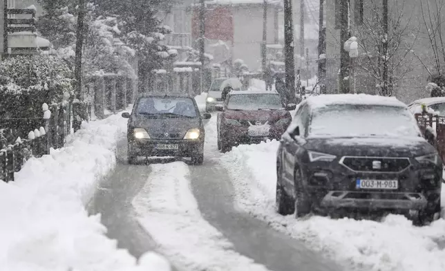 A car drives down the street during heavy snowfall in Bihac, Bosnia, Monday, Dec. 23, 2024. (AP Photo/Edvin Zulic)