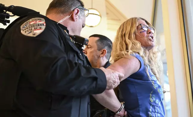 A demonstrator is placed under arrest after the Republican-dominated North Carolina House convened completed the override of Gov. Cooper's veto, Wednesday, Dec. 11, 2024, in Raleigh, N.C. (AP Photo/Matt Kelley)