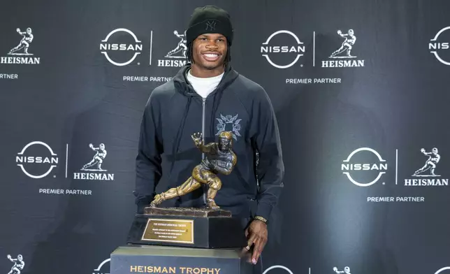 Heisman Trophy finalist Travis Hunter, of Colorado, poses with the trophy during a college football media availability, Friday, Dec. 13, 2024, in New York. (AP Photo/Corey Sipkin)