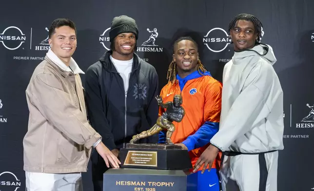 Heisman Trophy finalists, from left, Oregon's Dillon Gabriel, Colorado's Travis Hunter, Boise State's Ashton Jeanty and Miami's Cam Ward pose with the trophy during a college football media availability, Friday, Dec. 13, 2024, in New York. (AP Photo/Corey Sipkin)