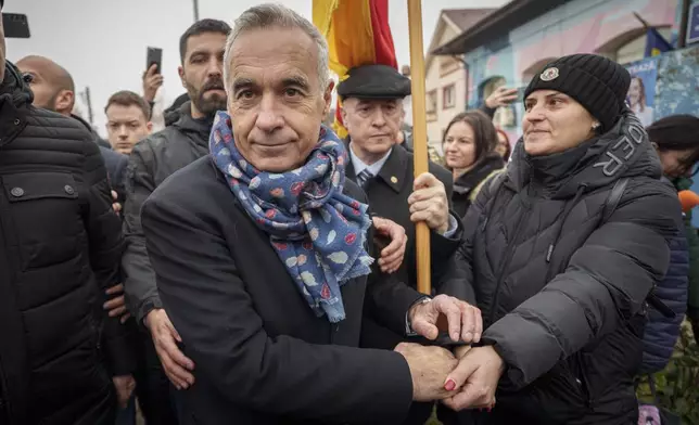 Calin Georgescu, center, an independent candidate for president who won the first round of presidential elections shakes with a supporter outside a closed voting station after Romania's Constitutional Court annulled the first round of presidential elections, in Mogosoaia, Romania, Sunday, Dec. 8, 2024. (AP Photo/Vadim Ghirda)