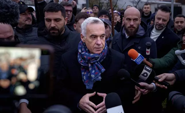 Calin Georgescu, center, an independent candidate for president who won the first round of presidential elections, speaks to media outside a voting station demanding to be allowed to vote after Romania's Constitutional Court annulled the first round of presidential elections, in Mogosoaia, Romania, Sunday, Dec. 8, 2024. (AP Photo/Andreea Alexandru)