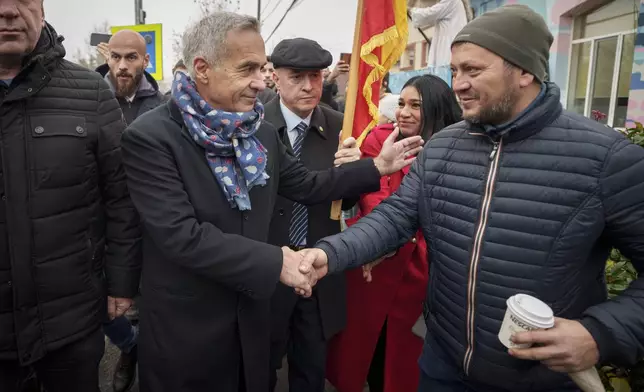 Calin Georgescu, front center, an independent candidate for president who won the first round of presidential elections shakes with a supporter outside a closed voting station after Romania's Constitutional Court annulled the first round of presidential elections, in Mogosoaia, Romania, Sunday, Dec. 8, 2024. (AP Photo/Vadim Ghirda)