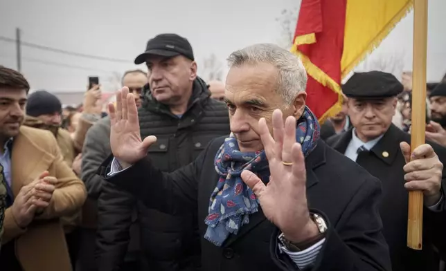 Calin Georgescu, foreground, an independent candidate for president who won the first round of presidential elections gestures outside a closed voting station after Romania's Constitutional Court annulled the first round of presidential elections, in Mogosoaia, Romania, Sunday, Dec. 8, 2024. (AP Photo/Vadim Ghirda)