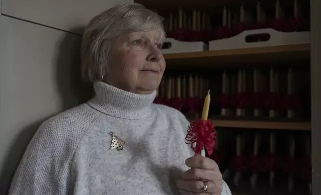 Central Moravian Church member Linda Thudium walked holds one of the thousands of handmade beeswax candles that her congregation will light during a Christmas service as part of a Moravian tradition in in Bethlehem, Pa., on Sunday, Dec. 1, 2024. (AP Photo/Luis Andres Henao)