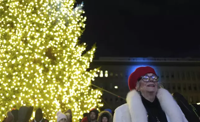 A woman smiles during the lighting of a Christmas tree on Payrow Plaza in Bethlehem, Pa., known as “Christmas City, USA,” on Sunday, Friday, Nov. 29, 2024. (AP Photo/Luis Andres Henao)