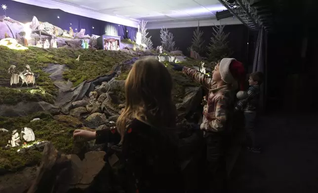 A boy points to miniature wooden figurines that are part of a Nativity scene in the community putz, a Moravian tradition that retells the story of the birth of Jesus, in Bethlehem, Pa., on Sunday, Dec. 1, 2024. (AP Photo/Luis Andres Henao)