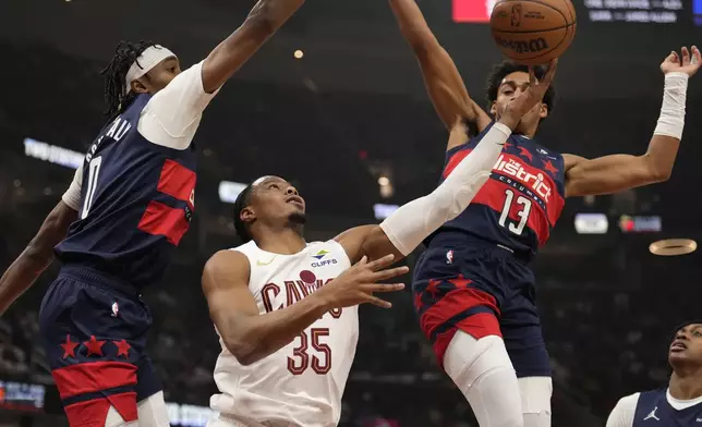 Cleveland Cavaliers forward Isaac Okoro (35) goes to the basket between Washington Wizards guard Bilal Coulibaly (0) and guard Jordan Poole (13) in the first half of an NBA basketball game, Friday, Dec. 13, 2024, in Cleveland. (AP Photo/Sue Ogrocki)