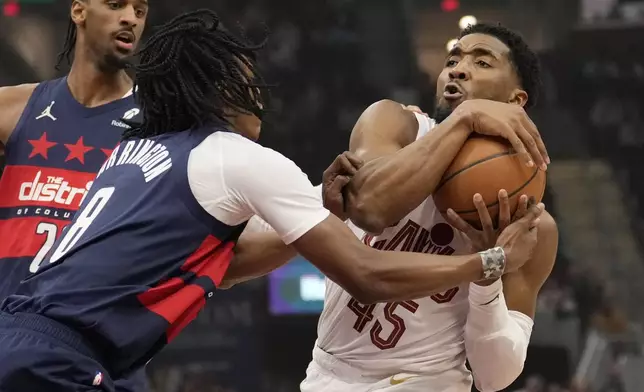 Cleveland Cavaliers guard Donovan Mitchell (45) is defended by Washington Wizards guard Bub Carrington (8) in the first half of an NBA basketball game, Friday, Dec. 13, 2024, in Cleveland. (AP Photo/Sue Ogrocki)