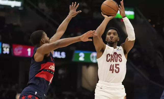 Cleveland Cavaliers guard Donovan Mitchell (45) shoots in front of Washington Wizards guard Jared Butler, left, in the first half of an NBA basketball game, Friday, Dec. 13, 2024, in Cleveland. (AP Photo/Sue Ogrocki)