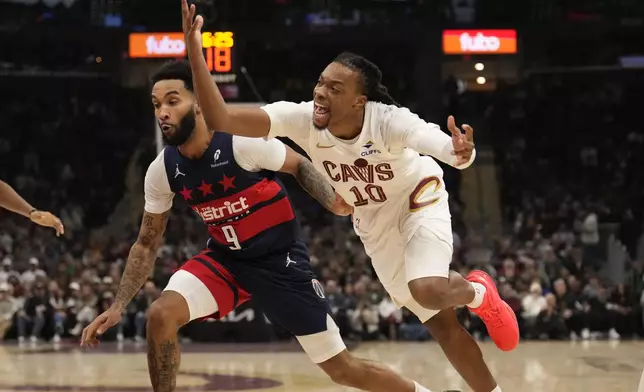 Cleveland Cavaliers guard Darius Garland (10) reacts after being striped of the ball and fouled by Anthony Gill, not in the photo, in the first half of an NBA basketball game, Friday, Dec. 13, 2024, in Cleveland. Wizards Justin Champagnie (9) is at left. (AP Photo/Sue Ogrocki)