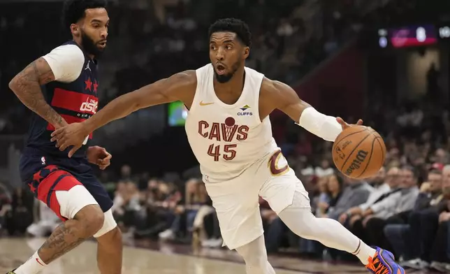 Cleveland Cavaliers guard Donovan Mitchell (45) drives around Washington Wizards forward Justin Champagnie, left, in the first half of an NBA basketball game, Friday, Dec. 13, 2024, in Cleveland. (AP Photo/Sue Ogrocki)