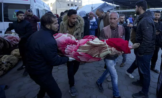 Palestinians carry the body of a relative killed in the Israeli bombardment of the Gaza Strip at a hospital in Deir al-Balah, Sunday, Dec. 15, 2024. (AP Photo/Abdel Kareem Hana)