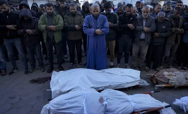 Palestinians pray next to the bodies of their relatives killed in the Israeli bombardment of the Gaza Strip, at a hospital in Deir al-Balah, Sunday, Dec. 15, 2024. (AP Photo/Abdel Kareem Hana)