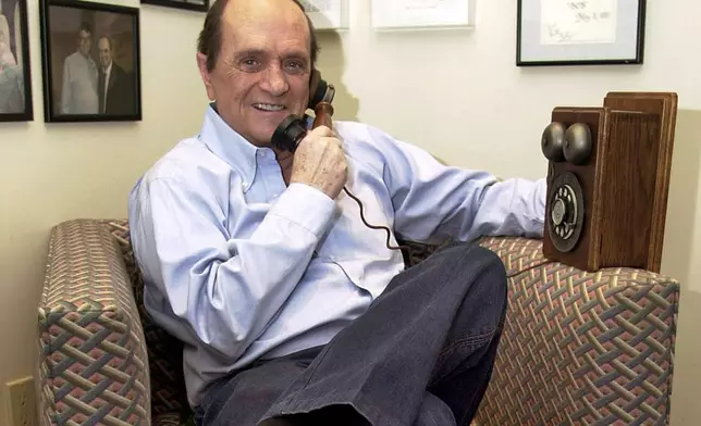 FILE - Comedian Bob Newhart pretends to speak on an antique telephone at his home in the Bel Air Estates community of Los Angeles, June 25, 2003. (AP Photo/Jerome T. Nakagawa, File)