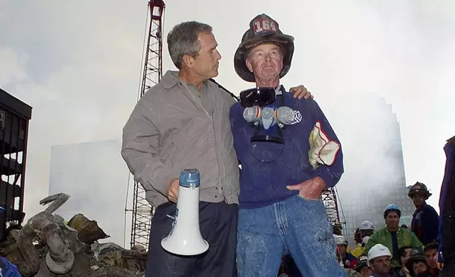 FILE — As rescue efforts continue in the rubble of the World Trade Center in New York, President George W. Bush, left, stands with New York City firefighter Bob Beckwith on a burnt fire truck in front of the World Trade Center during a tour of the devastation, Sept. 13, 2001. (AP Photo/Doug Mills, File)