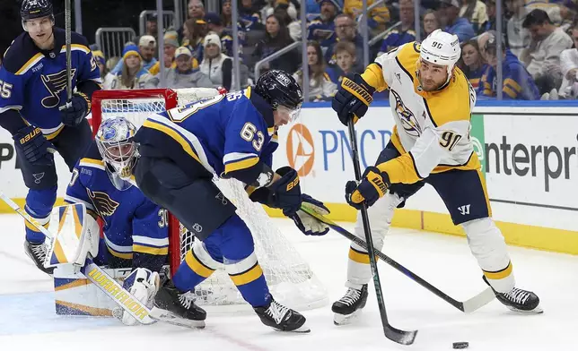 St. Louis Blues' Jake Neighbours (63) and Nashville Predators' Ryan O'Reilly (90) vie for control of the puck during the third period of an NHL hockey game Friday, Dec. 27, 2024, in St. Louis. (AP Photo/Scott Kane)