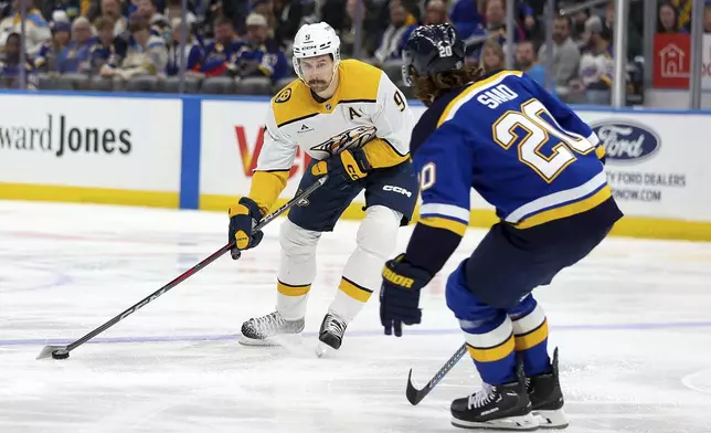 Nashville Predators' Filip Forsberg (9) controls the puck as St. Louis Blues' Brandon Saad (20) defends during the third period of an NHL hockey game Friday, Dec. 27, 2024, in St. Louis. (AP Photo/Scott Kane)