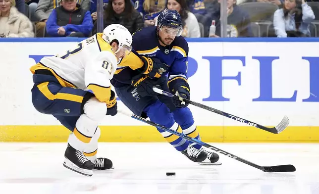 Nashville Predators' Adam Wilsby (83) and St. Louis Blues' Mathieu Joseph (71) vie for control of the puck during the second period of an NHL hockey game Friday, Dec. 27, 2024, in St. Louis. (AP Photo/Scott Kane)