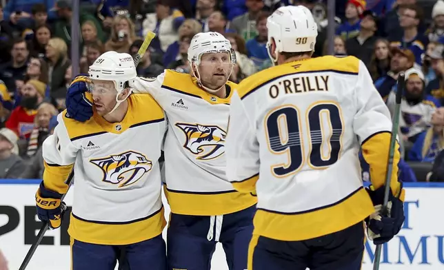 Nashville Predators' Jonathan Marchessault, left, is congratulated by teammates Steven Stamkos, center, and Ryan O'Reilly (90) after scoring during the third period of an NHL hockey game against the St. Louis Blues, Friday, Dec. 27, 2024, in St. Louis. (AP Photo/Scott Kane)