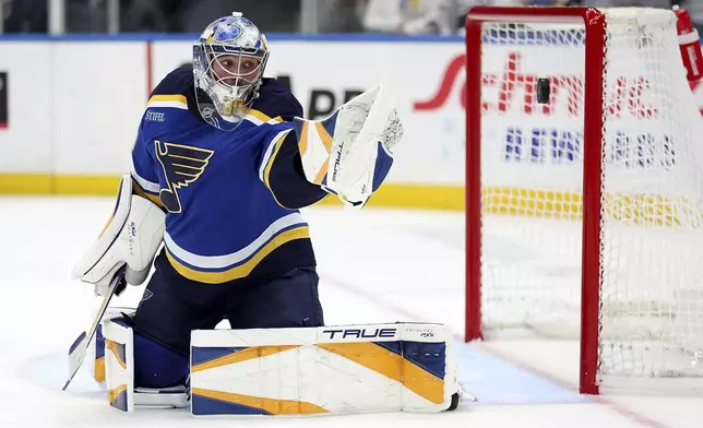 St. Louis Blues goaltender Joel Hofer (30) reaches for the buck as it flies past the gaol during the first period of an NHL hockey game against the Nashville Predators Friday, Dec. 27, 2024, in St. Louis. (AP Photo/Scott Kane)